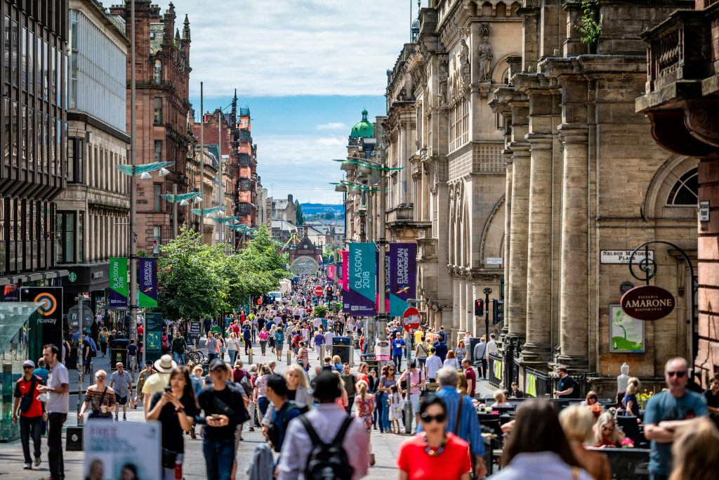 Crowded city street in Glasgow with people walking through the city centre